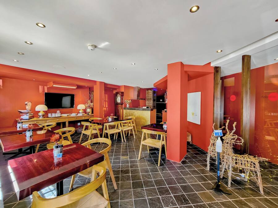 A dining area with a red wall, wooden furniture, and a tiled floor.