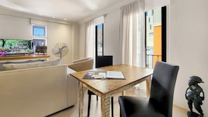 A modern hotel room with a dining area, a flat-screen TV, a fan, and a view of the city. - Rouge on Rose Boutique Hotel (Cape Town)