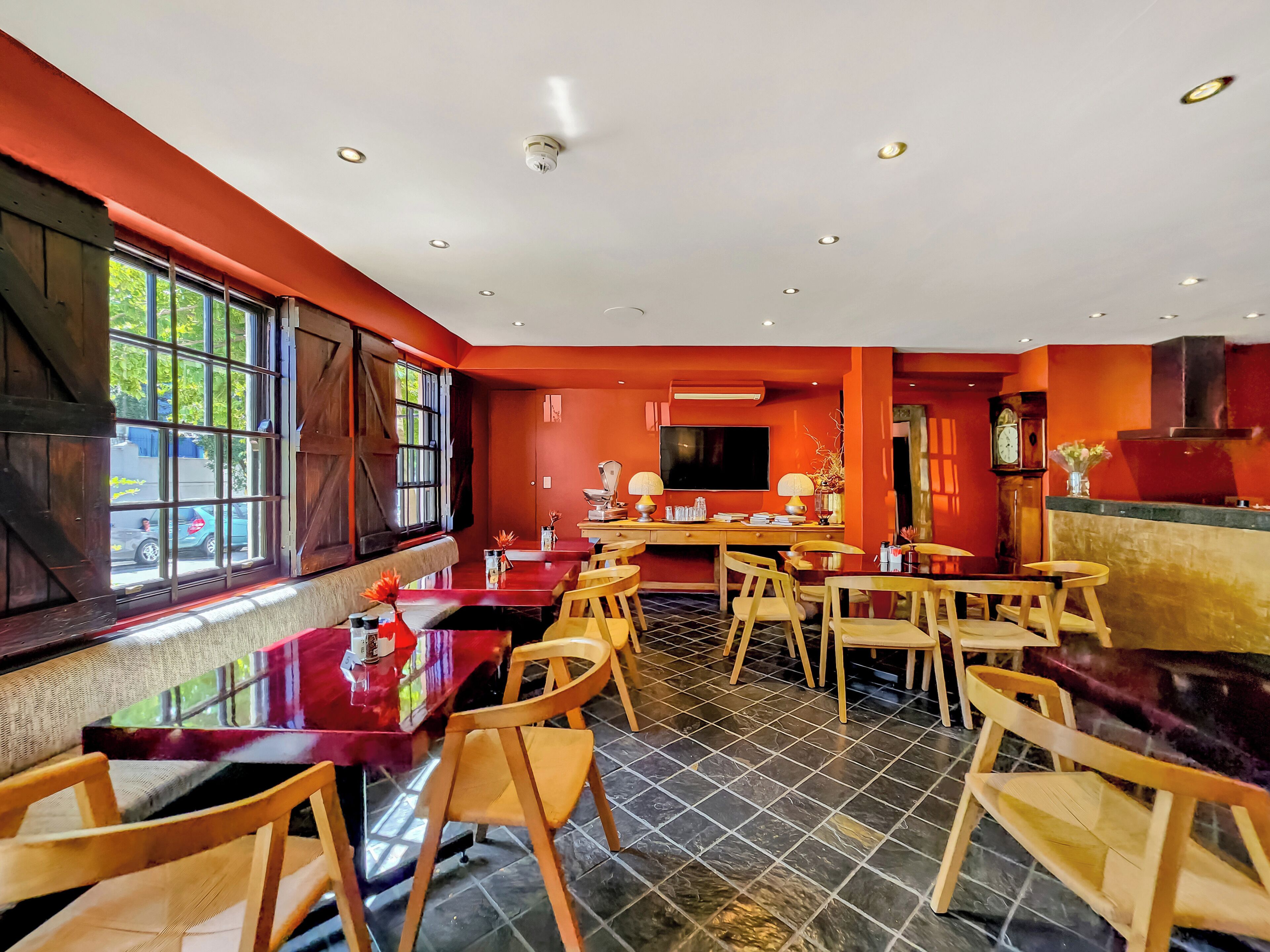 A restaurant with wooden tables and chairs, a large window, and a television.
