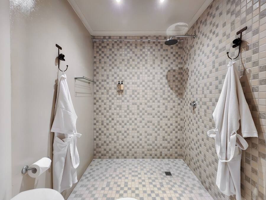 Een badkamer met een geruit vloertje, een douche en twee handdoeken aan haken.