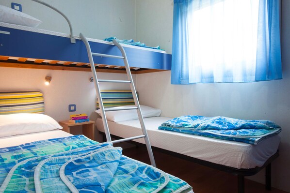 A bunk bed room with a ladder, a bedside table with books, and a window with curtains. - Camping Village Laguna Blu (Alghero)