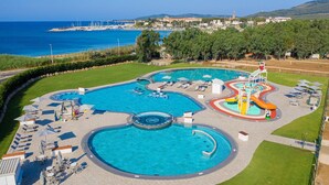 Una gran piscina al aire libre con varias secciones, incluyendo una piscina circular central y una zona de toboganes.