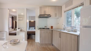Una cocina compacta con armarios de madera, una estufa a gas y un ventanal que proporciona luz natural.