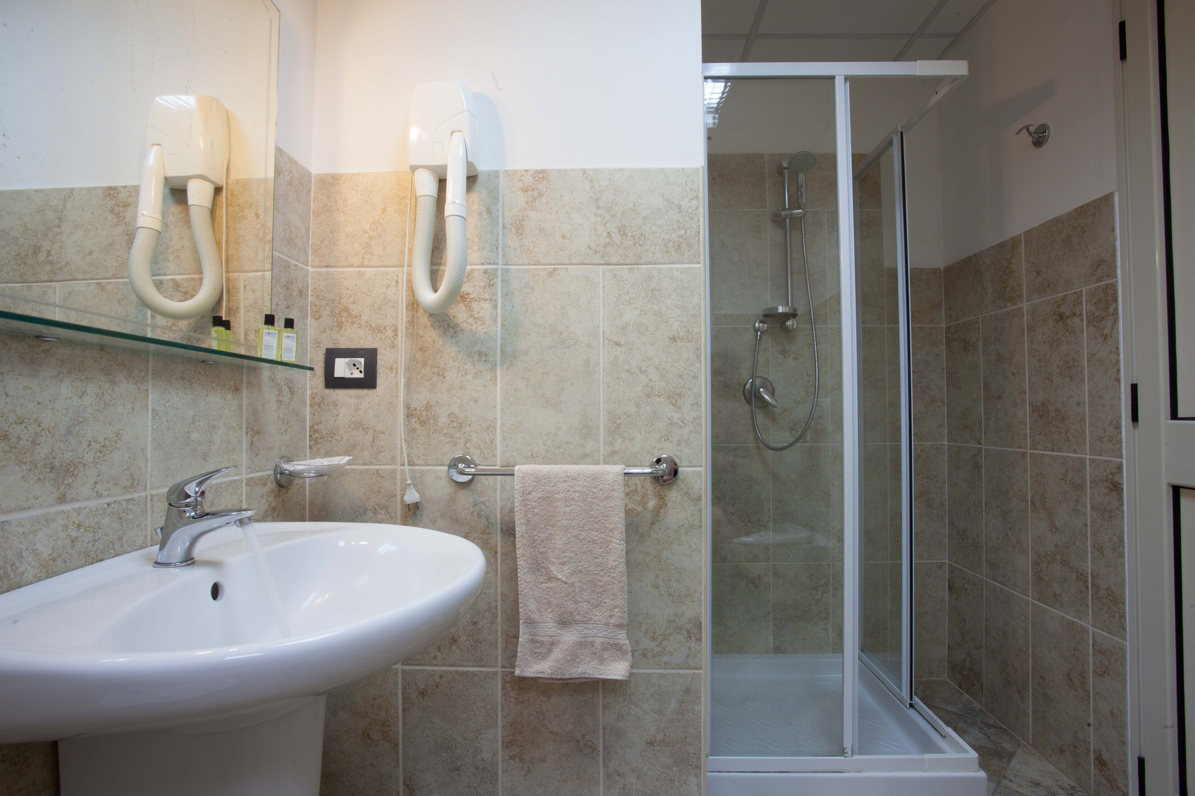 Un baño con un lavabo blanco, cabina de ducha con vidrio y un perchero para toallas.