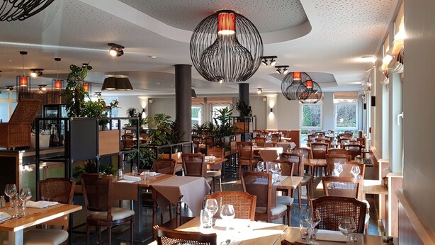 A spacious restaurant with multiple dining tables and chairs, modern pendant lighting, and a staircase leading to an upper level. - Hotel Gulliver (Käerjeng)