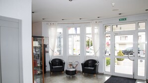 A reception area with two leather chairs, a glass display case, and a black doormat. - Hotel Gulliver (Käerjeng)