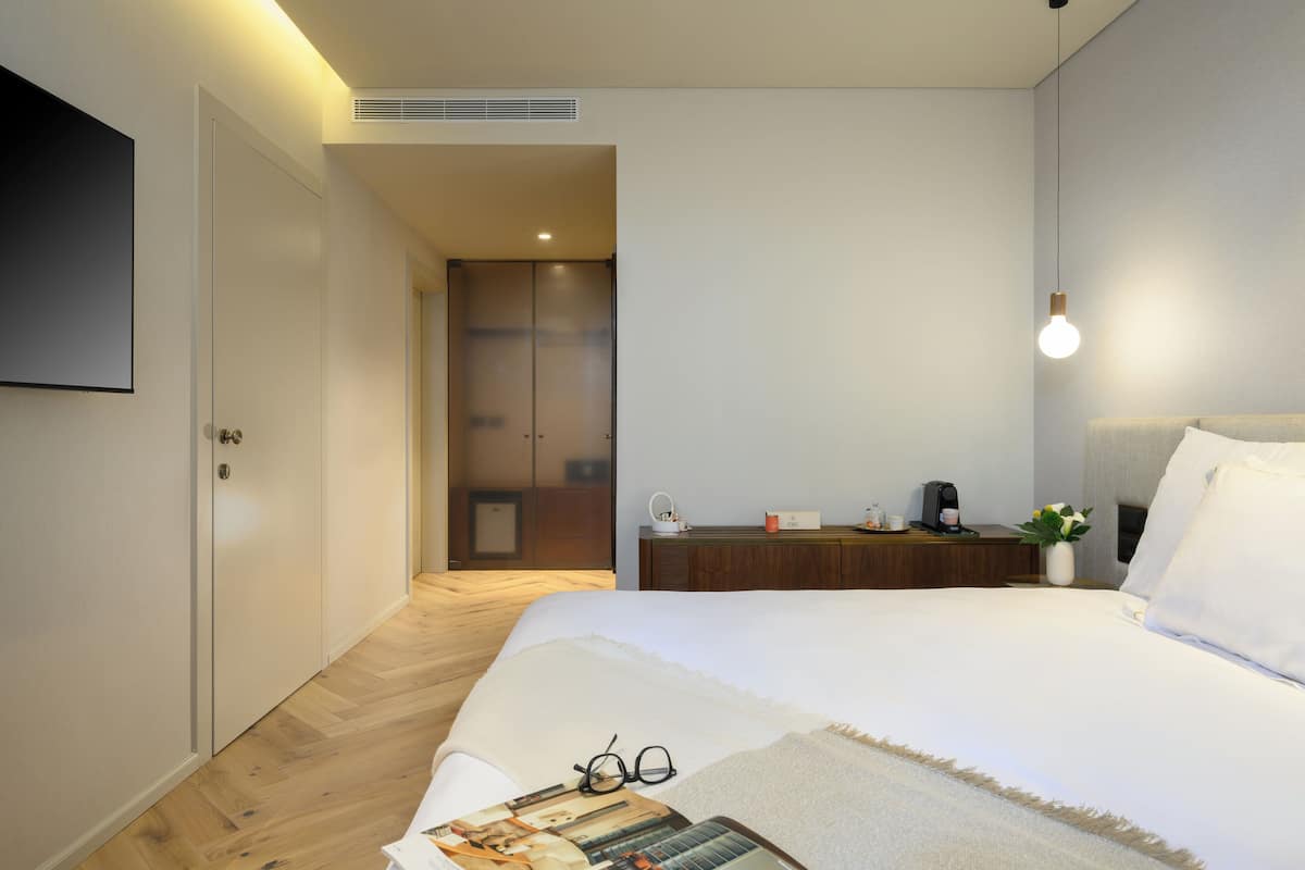 Un dormitorio moderno con una cama grande, una mesita de noche con lámpara, un armario y un espejo.