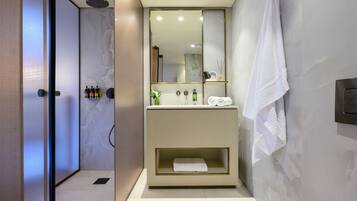 Un baño moderno con ducha a ras de suelo, tocador con espejo y toallero.