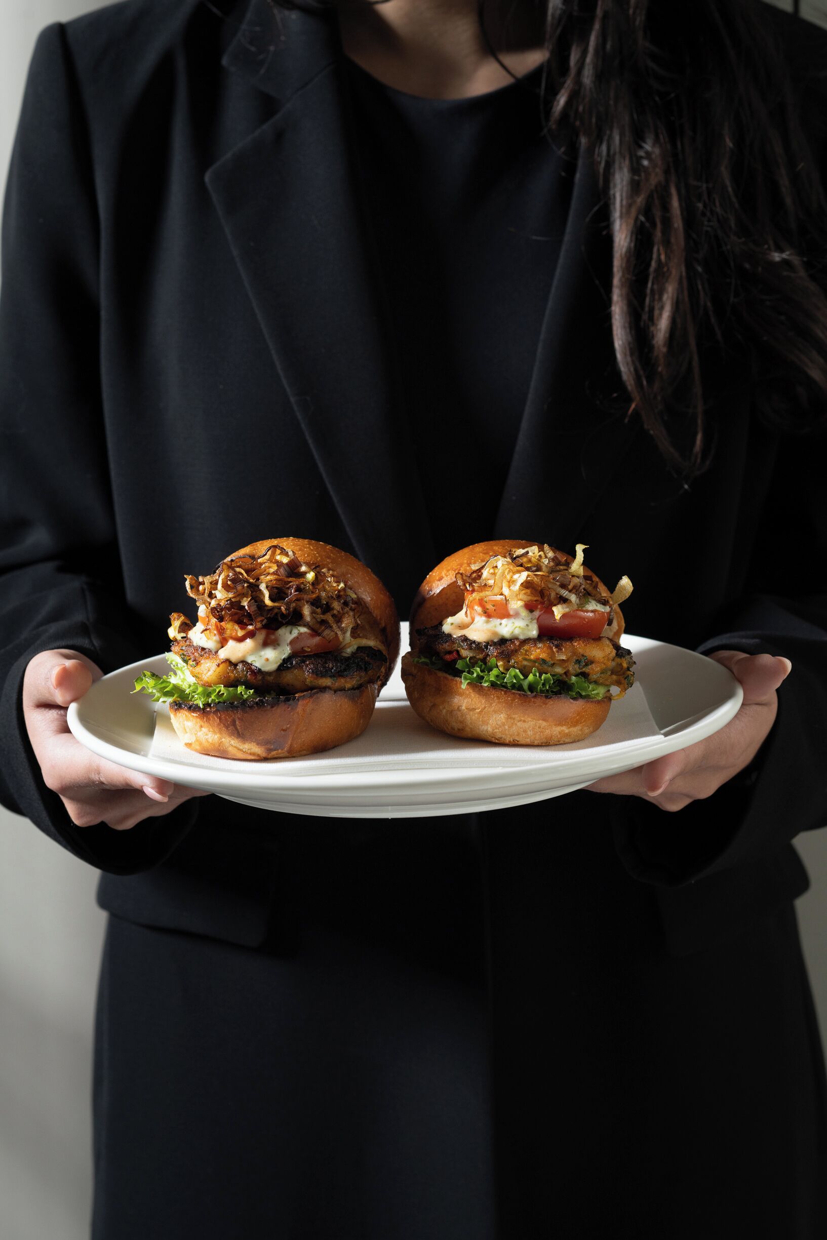 Iemand houdt een bord vast met twee hamburgers.