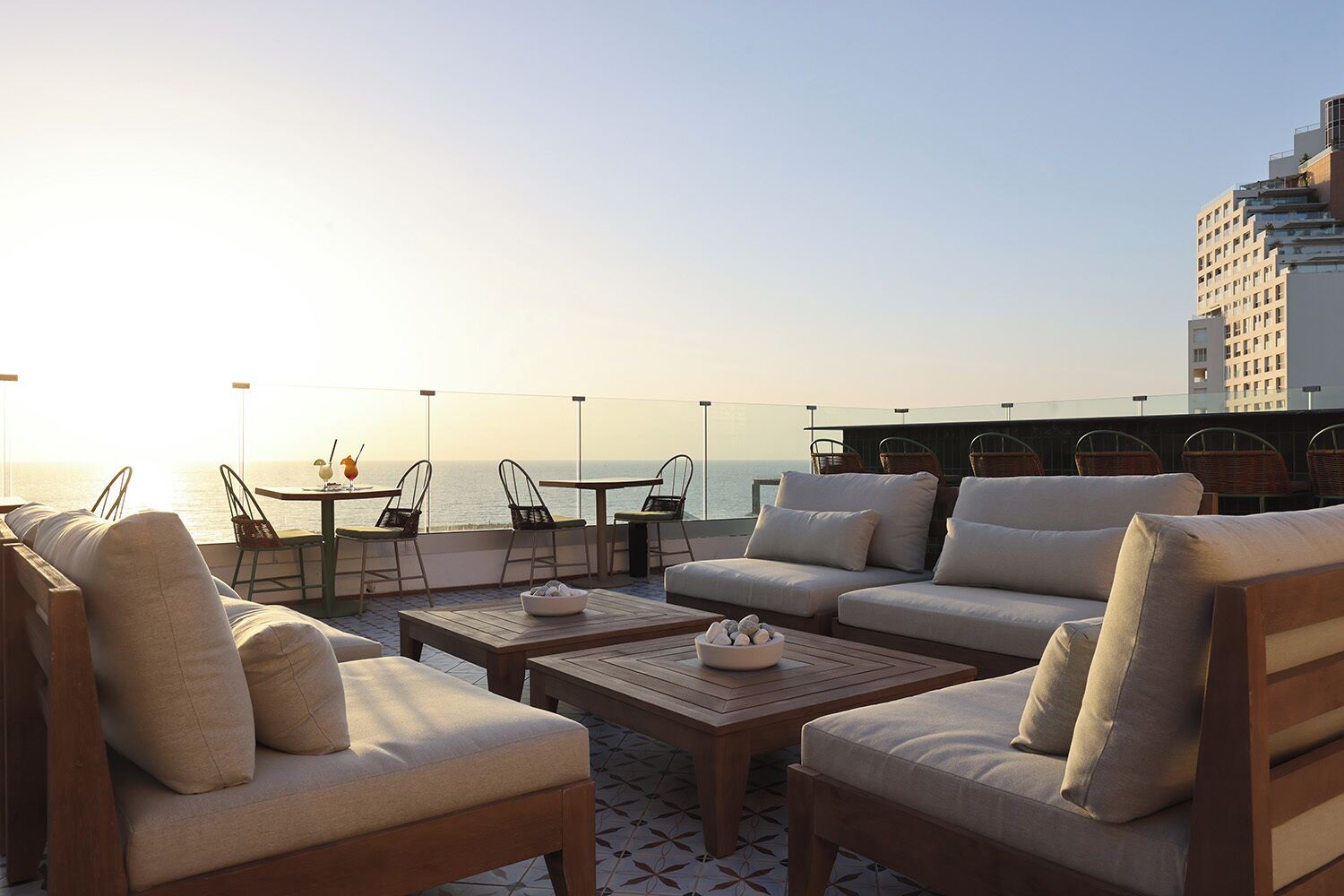 A rooftop terrace with outdoor seating, including sofas and chairs, overlooking a body of water.