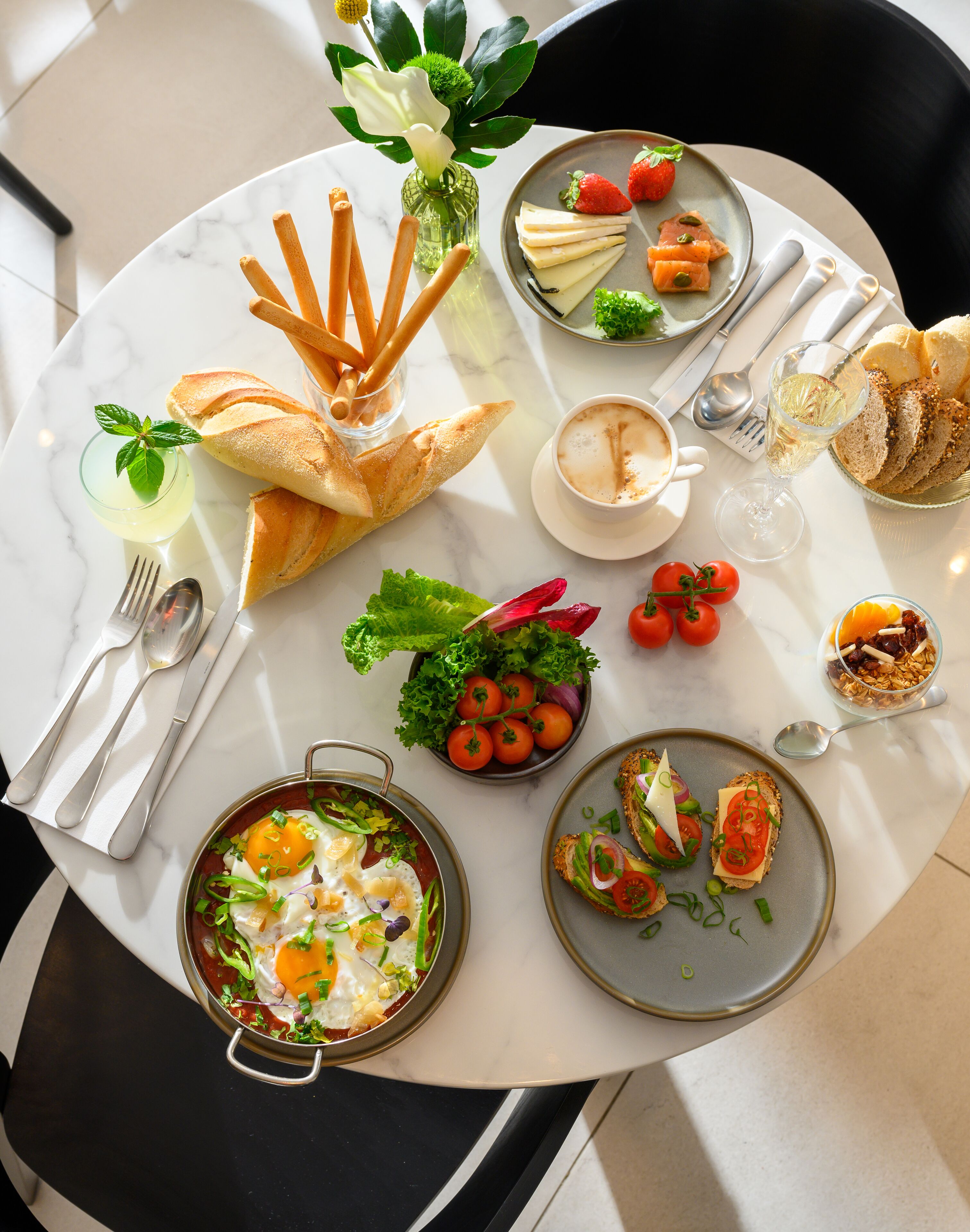 Una mesa redonda para comer con varios platos, incluyendo pan, ensalada y un tazón de sopa.