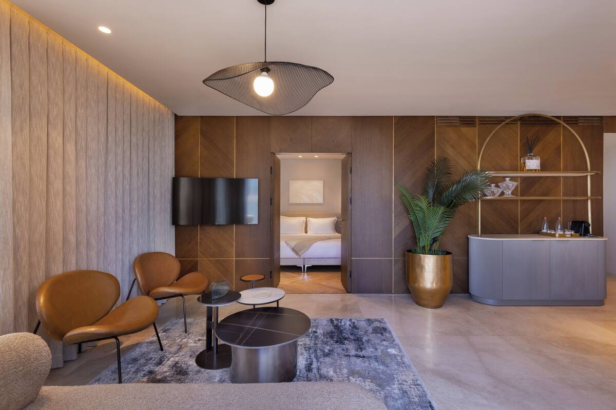 Un moderno vestíbulo de hotel con área de descanso, una recepción y una habitación visible a través de una puerta abierta.