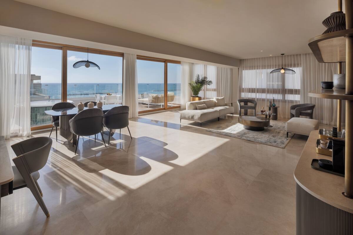 Amplia sala de estar con un ventanal que da al mar, un sofá moderno, una mesa de comedor y una mesa de centro.