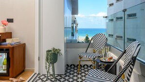 A balcony with a view of the sea, a chair, a small table with a drink and a dessert, and a potted plant. - Jewel Beachfront Boutique Hotel (Tel Aviv)