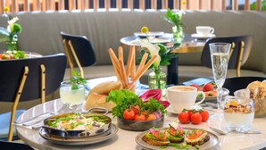 A dining table set with various dishes, including bread, tomatoes, and a glass of water. - Jewel Beachfront Boutique Hotel (Tel Aviv)