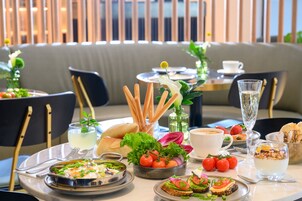 Una mesa de comedor dispuesta con varios platos, incluyendo pan, tomates y un vaso de agua.