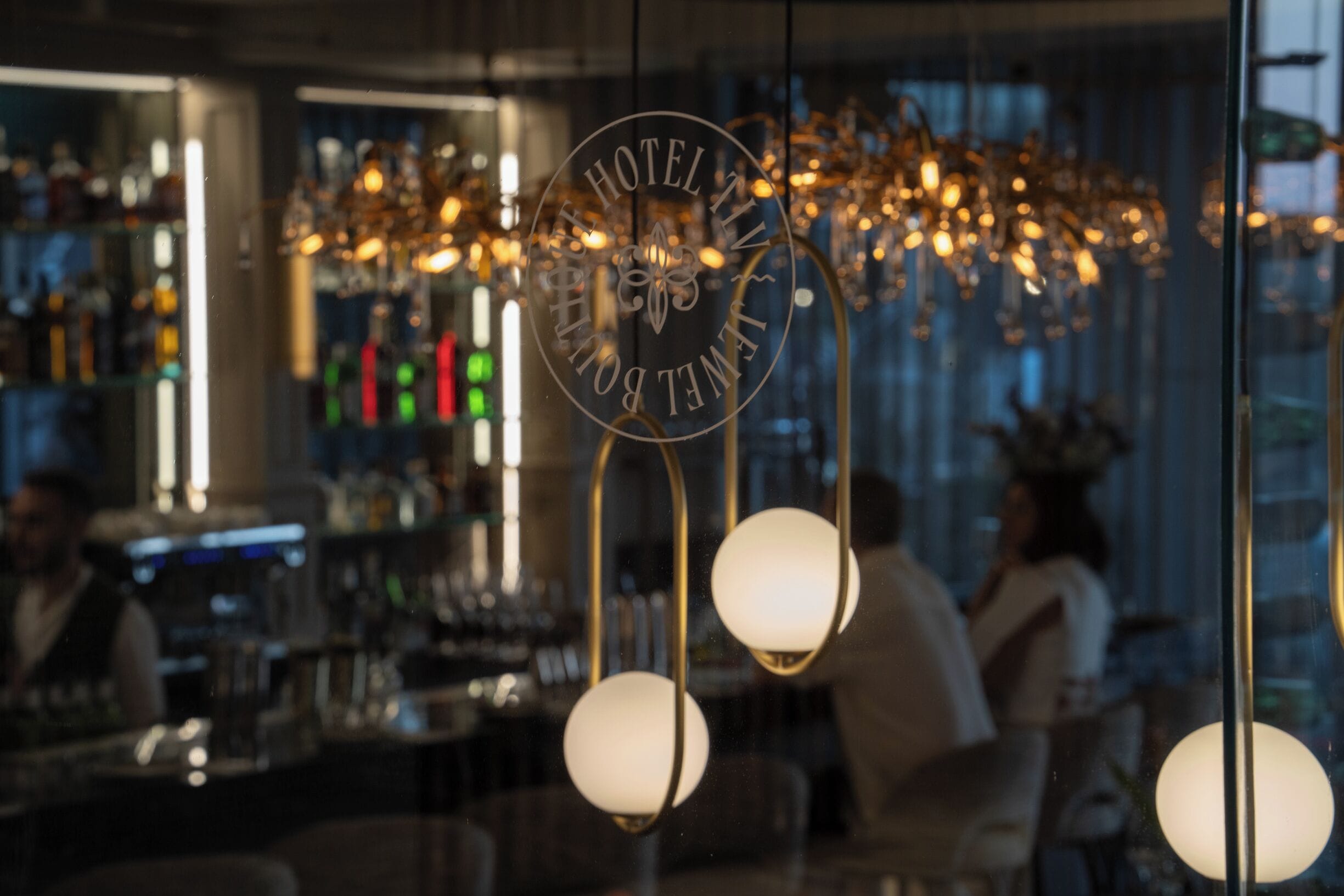 A bar area with hanging spherical light fixtures and a visible logo on the glass.