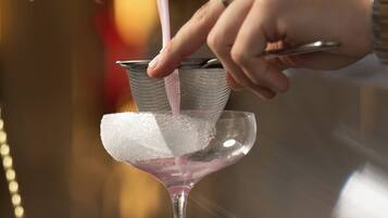 A person pouring a drink into a martini glass with a sugar rim.