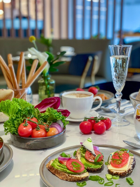 Una mesa de comedor con diversos alimentos, incluyendo un tazón de tomates y un vaso de agua.