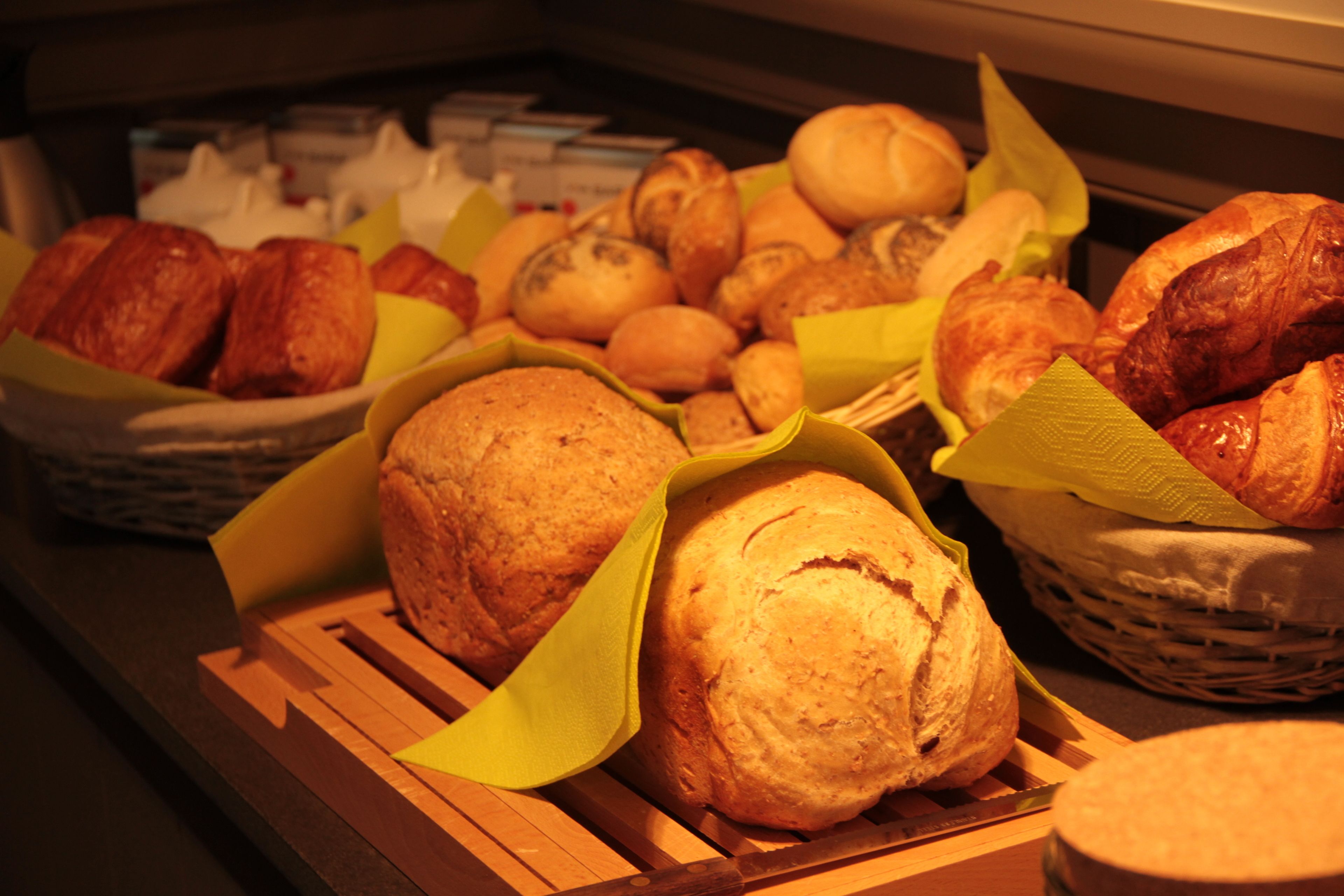 Una exhibición de panadería variada, con panes y pasteles, dispuesta sobre tablas y cestas de madera.