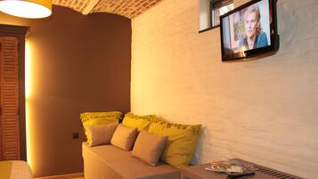 Una habitación acogedora con una cama, una mesita pequeña y un televisor montado en la pared.