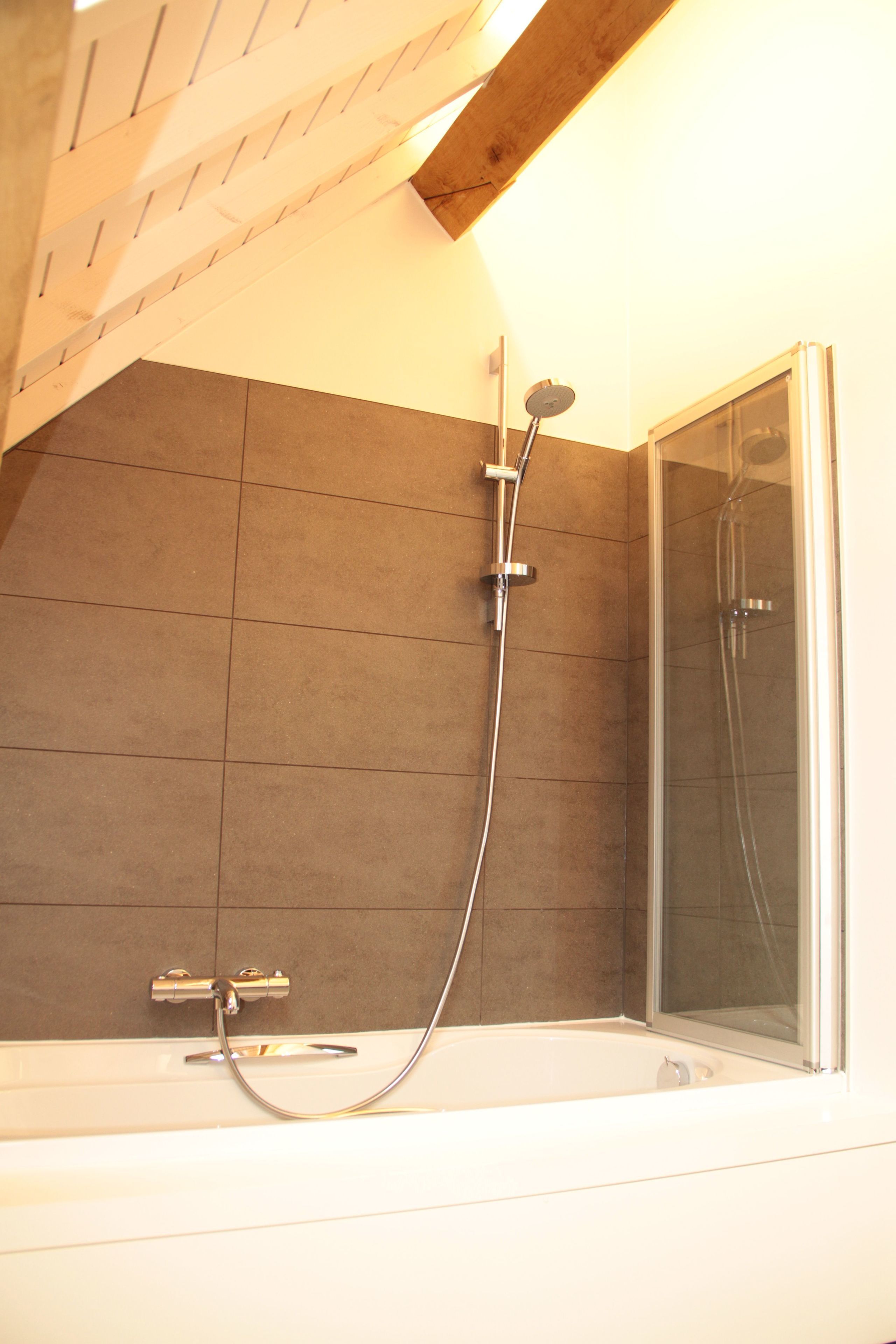 Een badkamer met een douche, een bad en een douchecabine met glazen wanden.