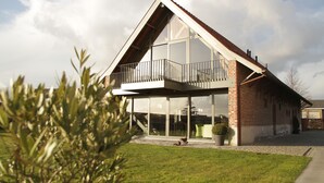 Une maison moderne à deux étages, dotée d’un grand balcon, d’un garage et d’une pelouse bien entretenue.
