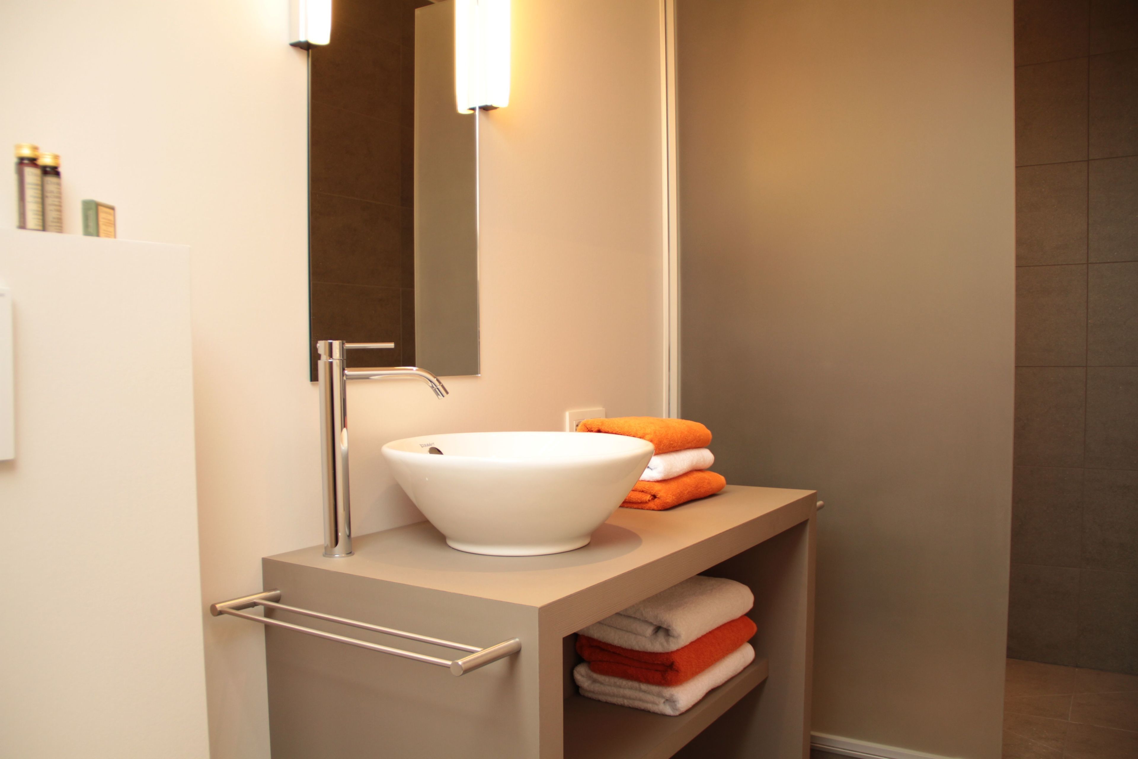 A modern bathroom with a white sink, a mirror, and a towel rack.