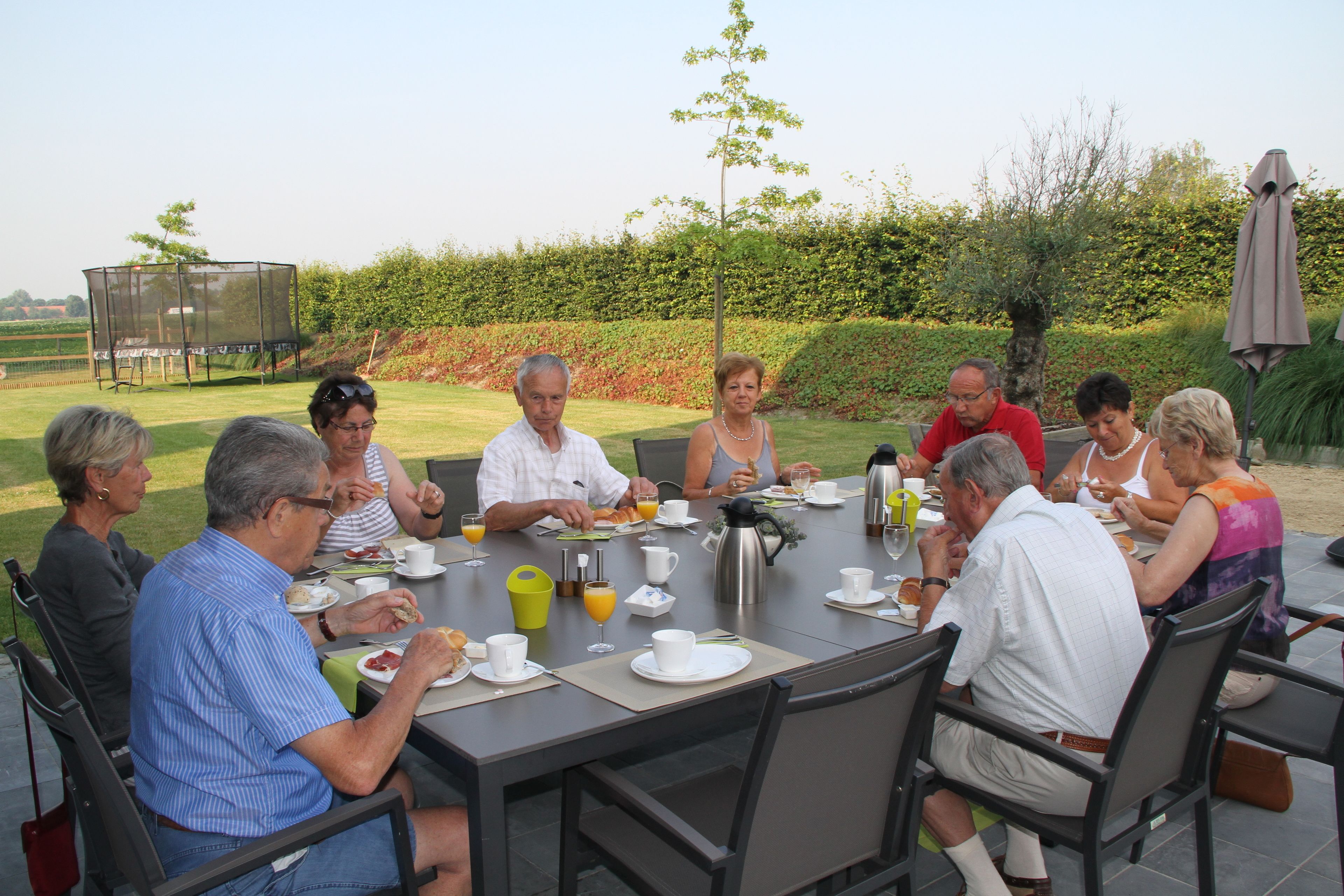 Een groep mensen zit buiten aan een tafel te eten.