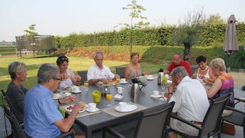 Een groep mensen zit buiten aan een tafel te eten.