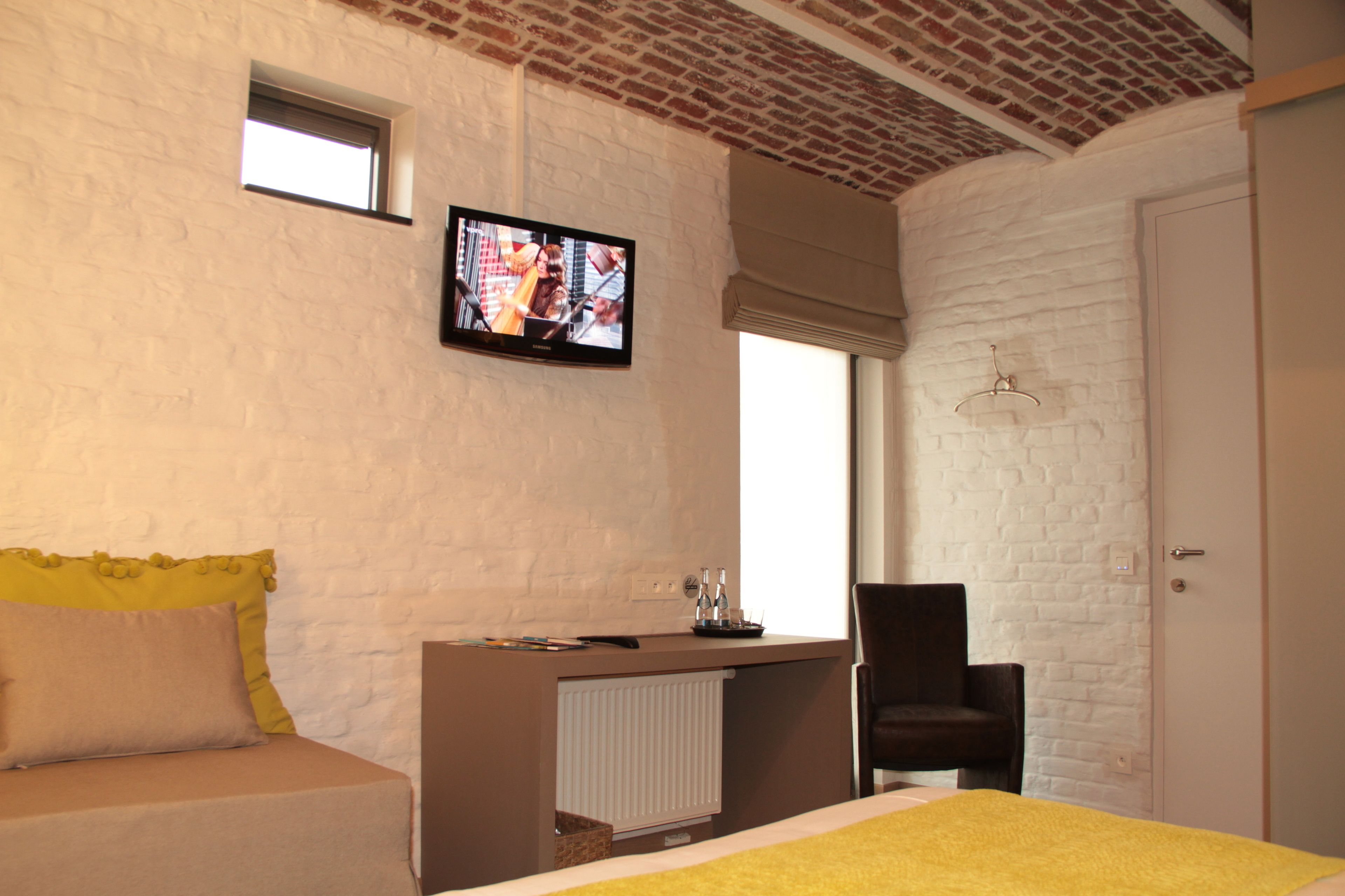 Een slaapkamer met een bed, een bureau, een stoel, een televisie en een raam.