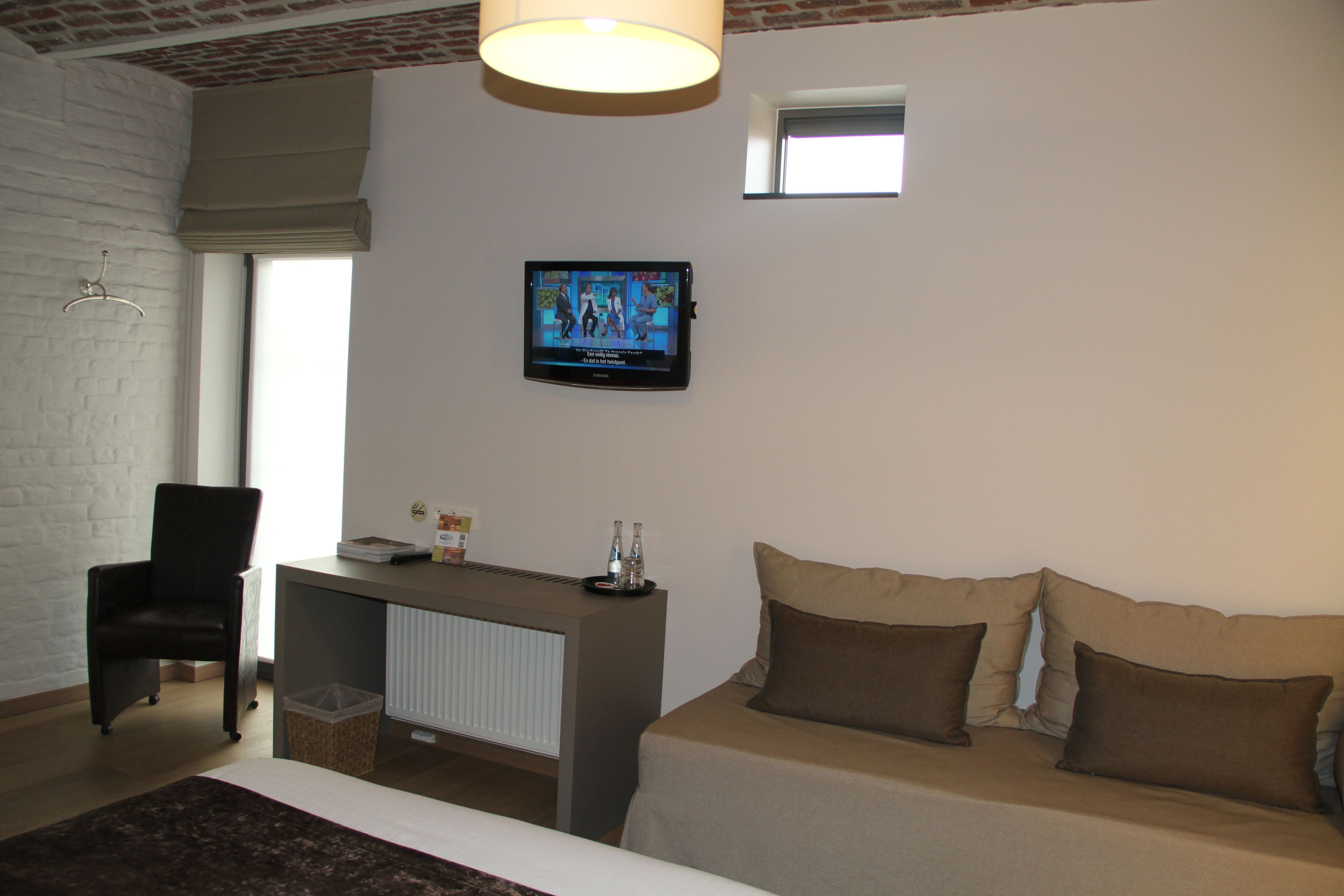 Hotellihuone, jossa on sänky, työpöytä, tuoli, televisio ja ikkuna.