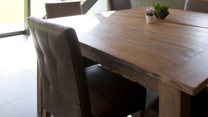 Un espace repas avec une table en bois, des chaises en cuir et un escalier en briques.