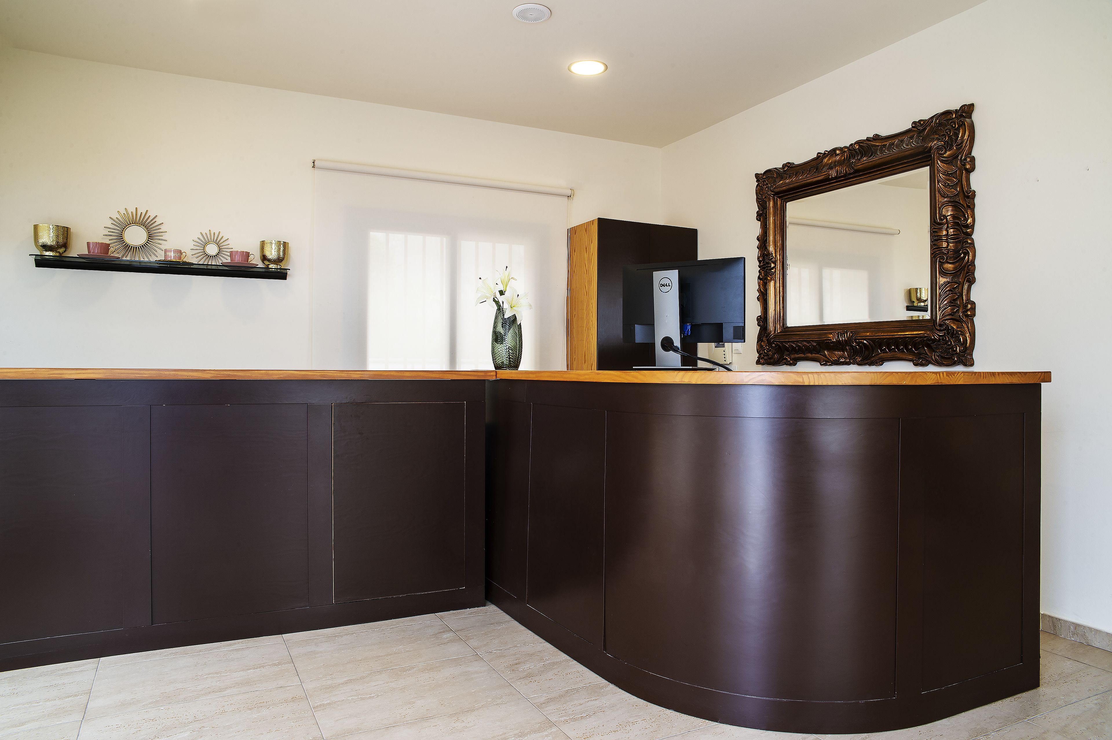 Una cocina moderna con armarios oscuros, encimera de madera y un espejo grande.