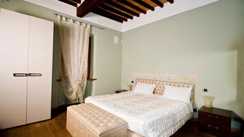 A bedroom with a large bed, a wardrobe, a bench, and a nightstand.