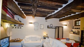 Un salon chaleureux avec deux canapés blancs, un téléviseur et un coin repas comprenant une table et des chaises.