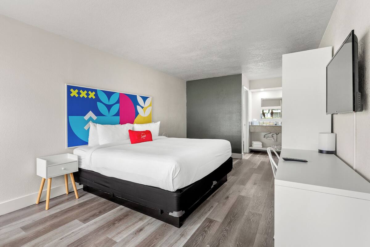 A modern bedroom with a bed, bedside table, and a large mirror.