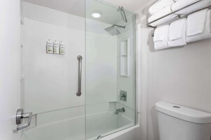Ein modernes Badezimmer mit einer Glaskabinentrennung für die Dusche, einer Toilette und einem Handtuchhalter.