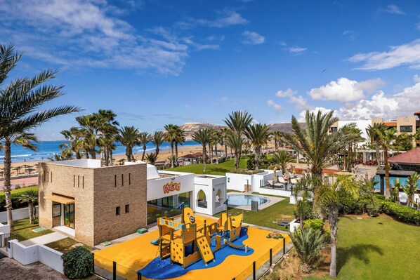 A resort with a pool, palm trees, and a beach view.