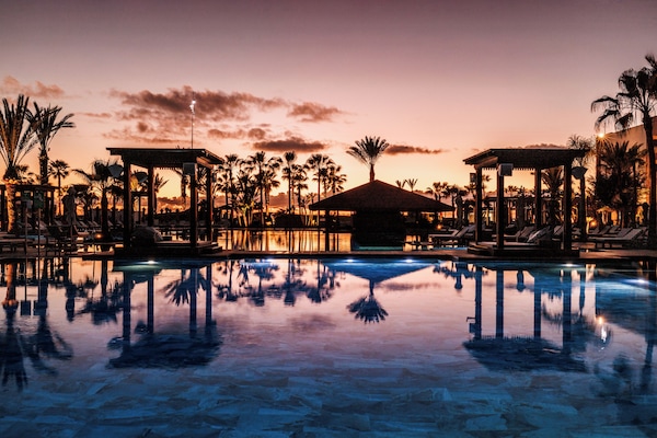 Una piscina techada, una piscina al aire libre, sombrillas