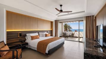 A hotel room with a bed, bedside table, chair, TV, and a balcony with a view of the sea.
