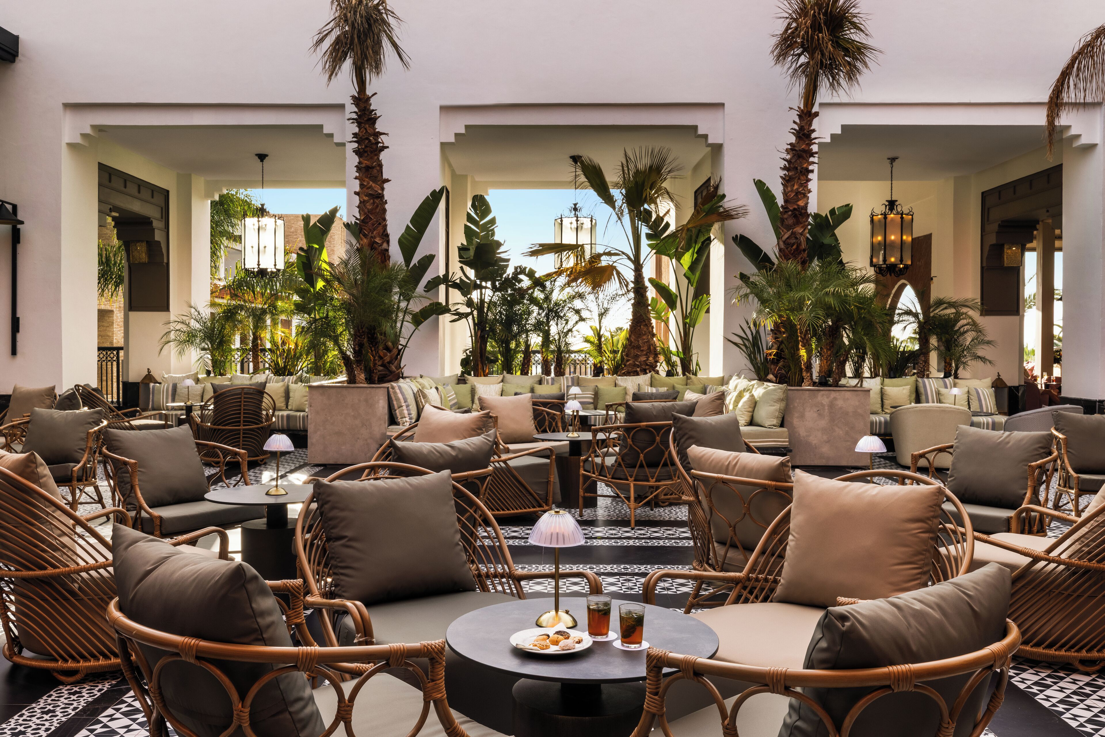 Amplia sala de estar con muebles de mimbre, una mesa central con bebidas y vistas al exterior.