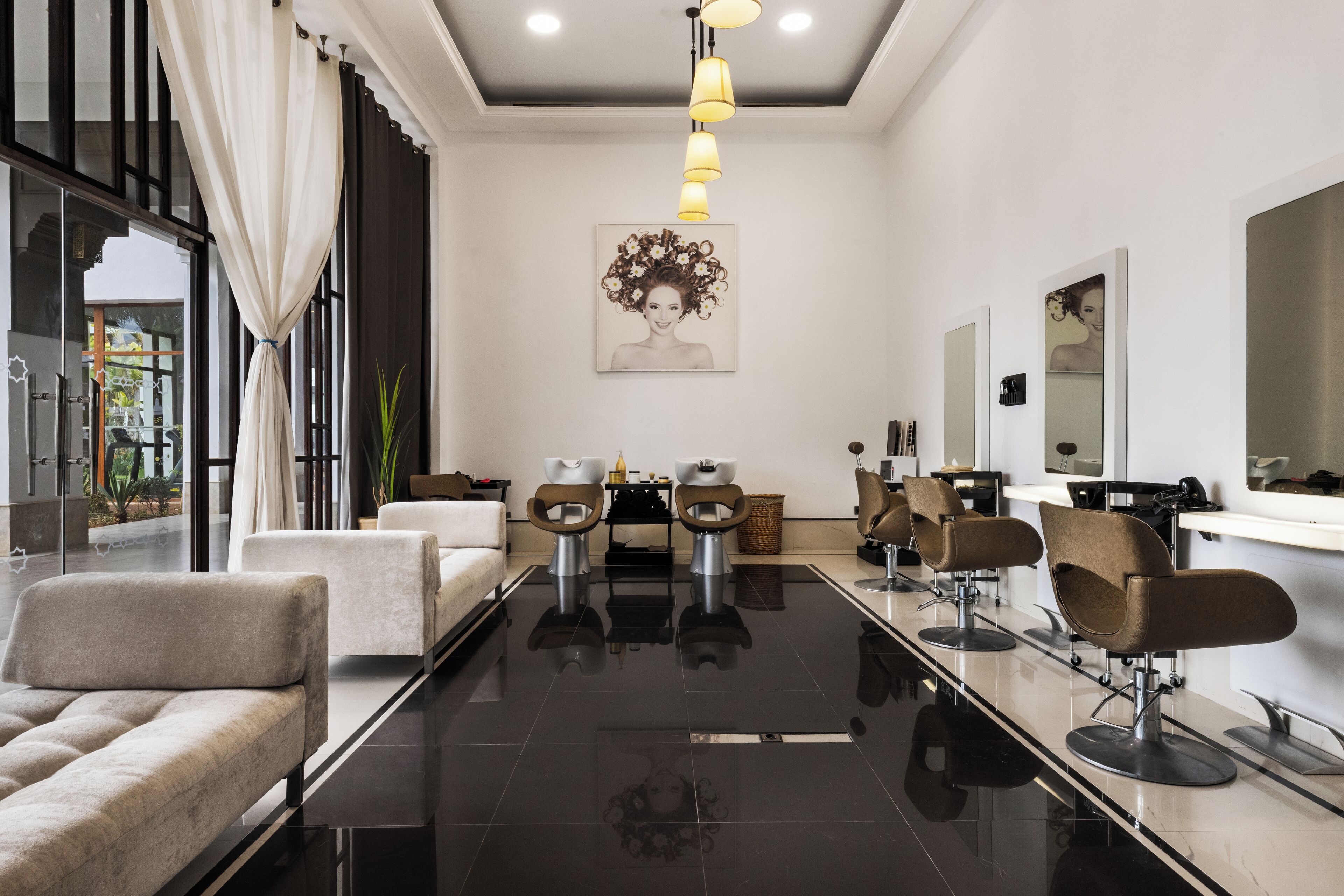 A modern salon with a long reception desk, multiple hairdressing chairs, and a large mirror.