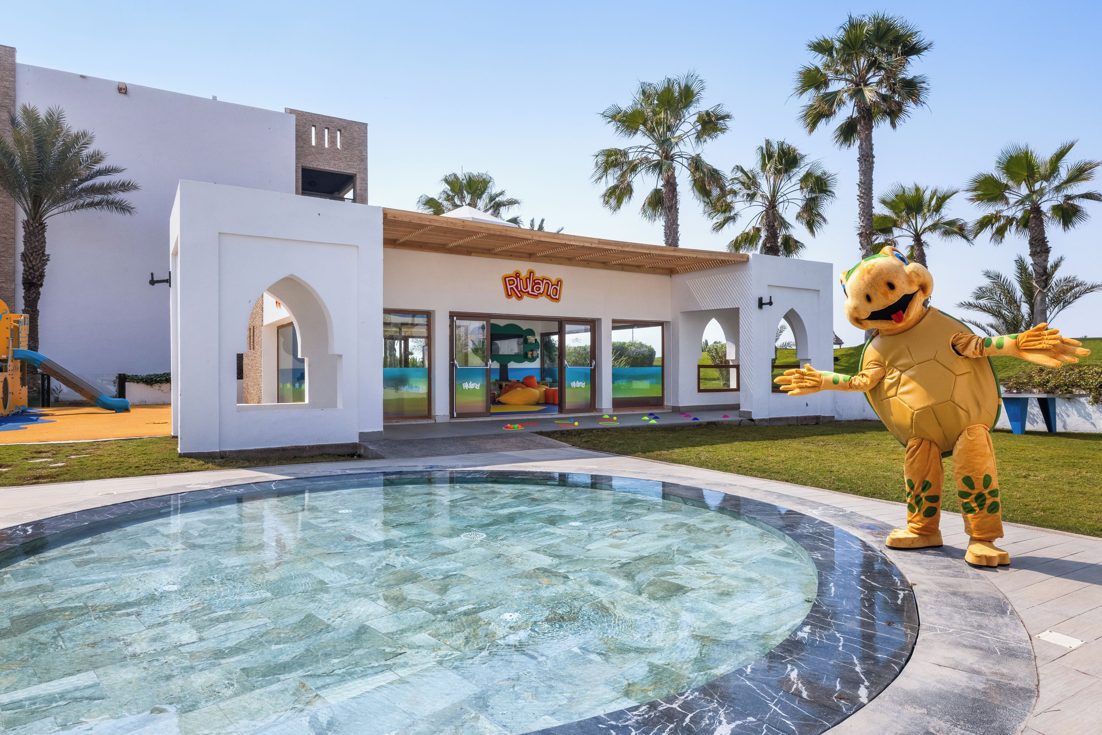 A building with a sign reading "Rivend", a pool area, and a mascot in a costume.