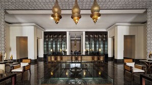 A spacious lobby with a reflective glass coffee table, ornate chandeliers, and a bar area with seating. - Hotel Riu Palace Tikida Agadir - All Inclusive (Agadir)