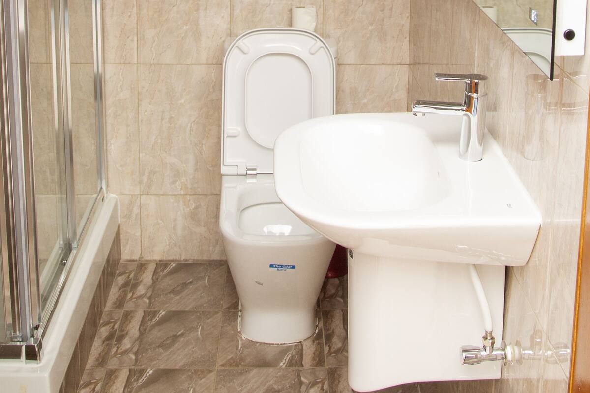 Ein Badezimmer mit Toilette, Waschbecken und einer Duschkabine aus Glas.