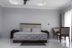 Un dormitorio moderno con una cama grande, mesitas de noche, una silla y un escritorio.
