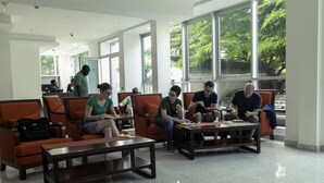A modern waiting area with orange seating, large windows, and a clean, tiled floor. - Monarch Hotel (Accra)