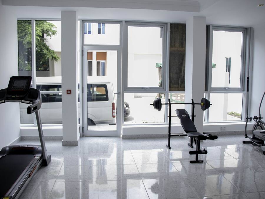 Ein Fitnessraum mit Laufband, Langhantelbank und Crosstrainer.