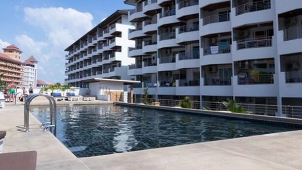 Un hôtel moderne doté d’une piscine, de nombreux balcons et offrant une vue sur d’autres immeubles.